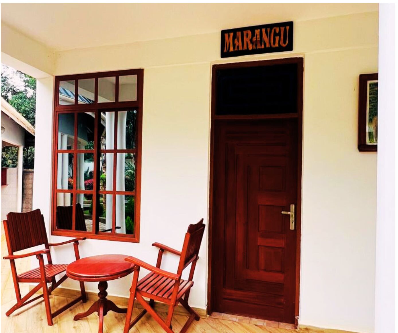 A room with a wooden door, a window with multiple panes, and two wooden chairs around a small table.