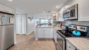 Una cocina moderna con muebles blancos, electrodomésticos de acero inoxidable y una isla central.