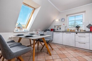 Ett modernt kök med en matplats, med ett bord för fyra personer, en klocka på väggen och ett fönster med utsikt.
