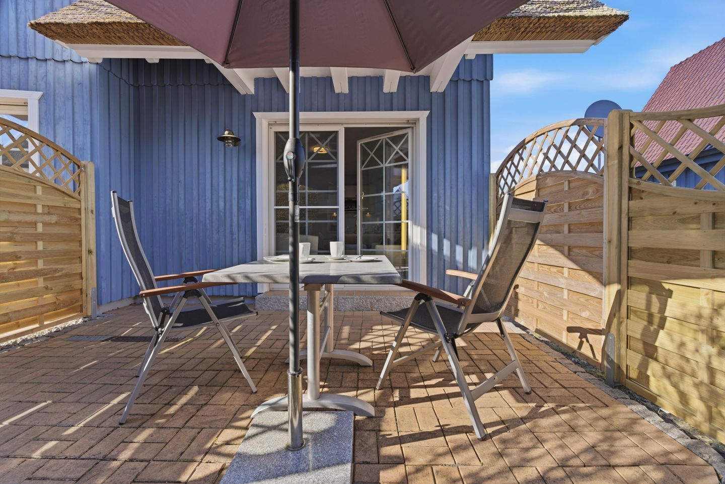 A patio with a table and chairs, a pergola, and a wooden fence.