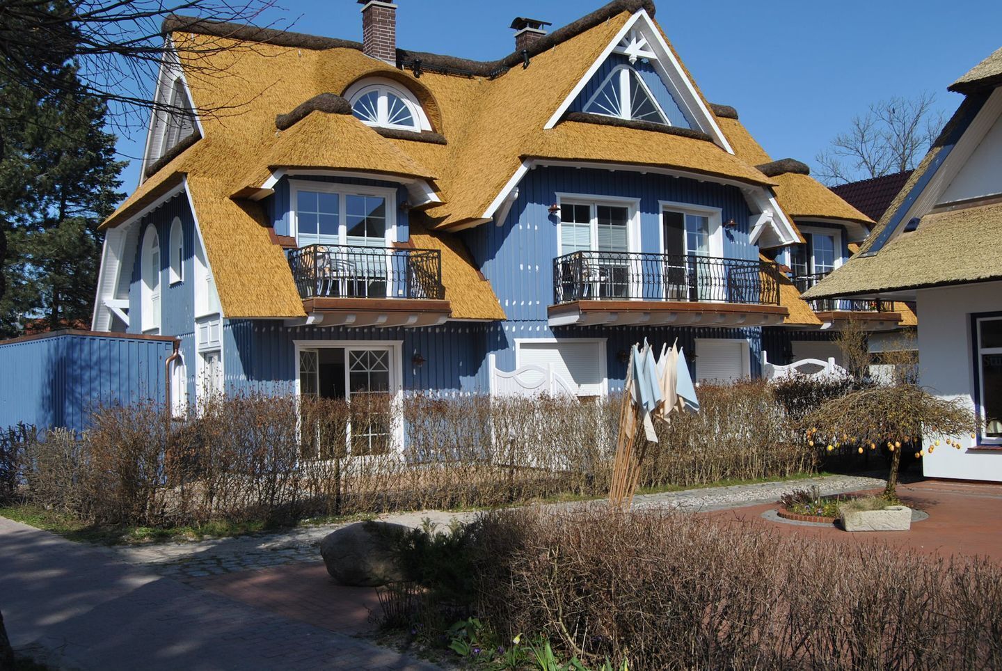 A two-story house with a thatched roof, large windows, and a balcony.