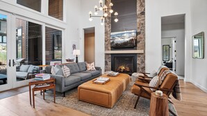A spacious living room with a fireplace, a large sofa, a coffee table, and a stone accent wall. - Red Ledges vista, hottub, golf, min 90 day stay (Heber City)