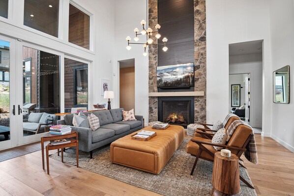 A spacious living room with a fireplace, a large sofa, a coffee table, and a stone accent wall. - Red Ledges vista, hottub, golf, min 90 day stay (Heber City)