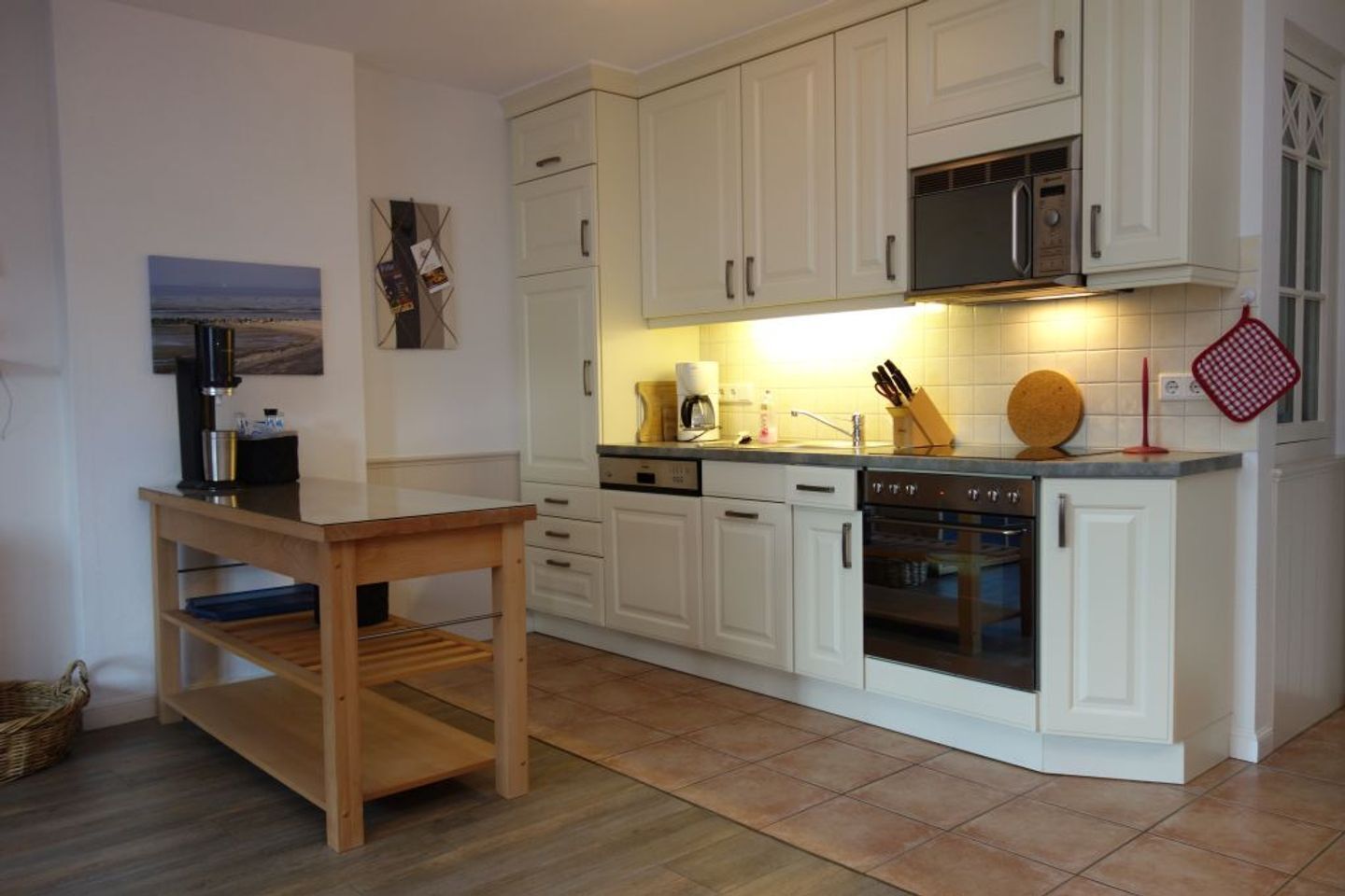 Una cocina moderna con armarios blancos, una mesa de madera y un horno empotrado.