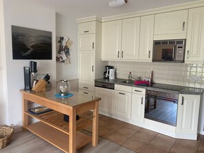 A compact kitchen with white cabinets, a built-in microwave, a coffee maker, and a dishwasher.