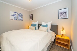 A neatly arranged bedroom with a large bed, two bedside tables, and wall art.