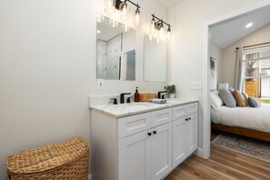 Un bagno moderno con un mobile lavabo bianco, uno specchio grande e un box doccia con motivo geometrico.