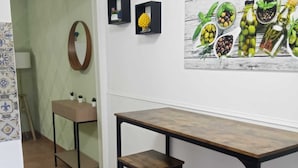 A kitchen with a wooden table and two stools, a mirror, and a wall-mounted shelf with decorative items. - Studio apartment with kitchen in Center "Stay in Catania" (Catania)