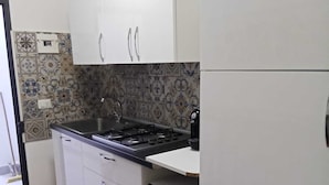 A compact kitchen with white cabinets, a gas stove, and a microwave. - Studio apartment with kitchen in Center "Stay in Catania" (Catania)