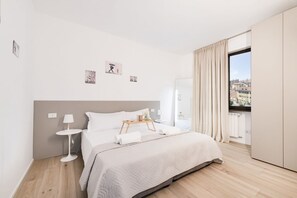 A modern hotel room with a large bed, a bedside table, a small side table, and a window with curtains. - Easylife - Contemporary design on the Navigli (Milano)