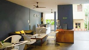 A modern living room with a sofa, chairs, a coffee table, and a kitchen area with a refrigerator and sink. - Skazka Beach Resort (Mandrem)