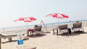 A beach with wooden lounge chairs and red umbrellas. - Skazka Beach Resort (Mandrem)