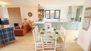 A cozy living room with a sofa, a TV, and a dining area with a table set for four. - Sandy Toes (Mablethorpe)