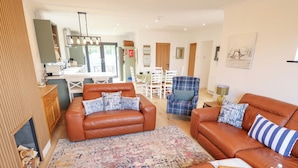 A spacious living room with leather sofas, a patterned rug, and a dining area with a table and chairs. - Sandy Toes (Mablethorpe)