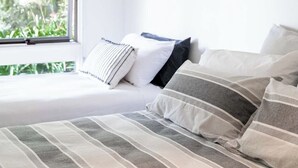 A bedroom with a bed, pillows, and a window with a view of greenery. - Seaside Country Escape (Torquay)