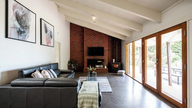 A modern living room with a brick fireplace, a leather sofa, and a flat-screen TV. - Seaside Country Escape (Torquay)