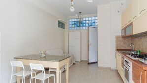 A modern kitchen with a dining area, featuring a granite countertop, white chairs, and a built-in oven. - Giardino Degli Aranci With Terrace by Wonderful Italy (Taormina)