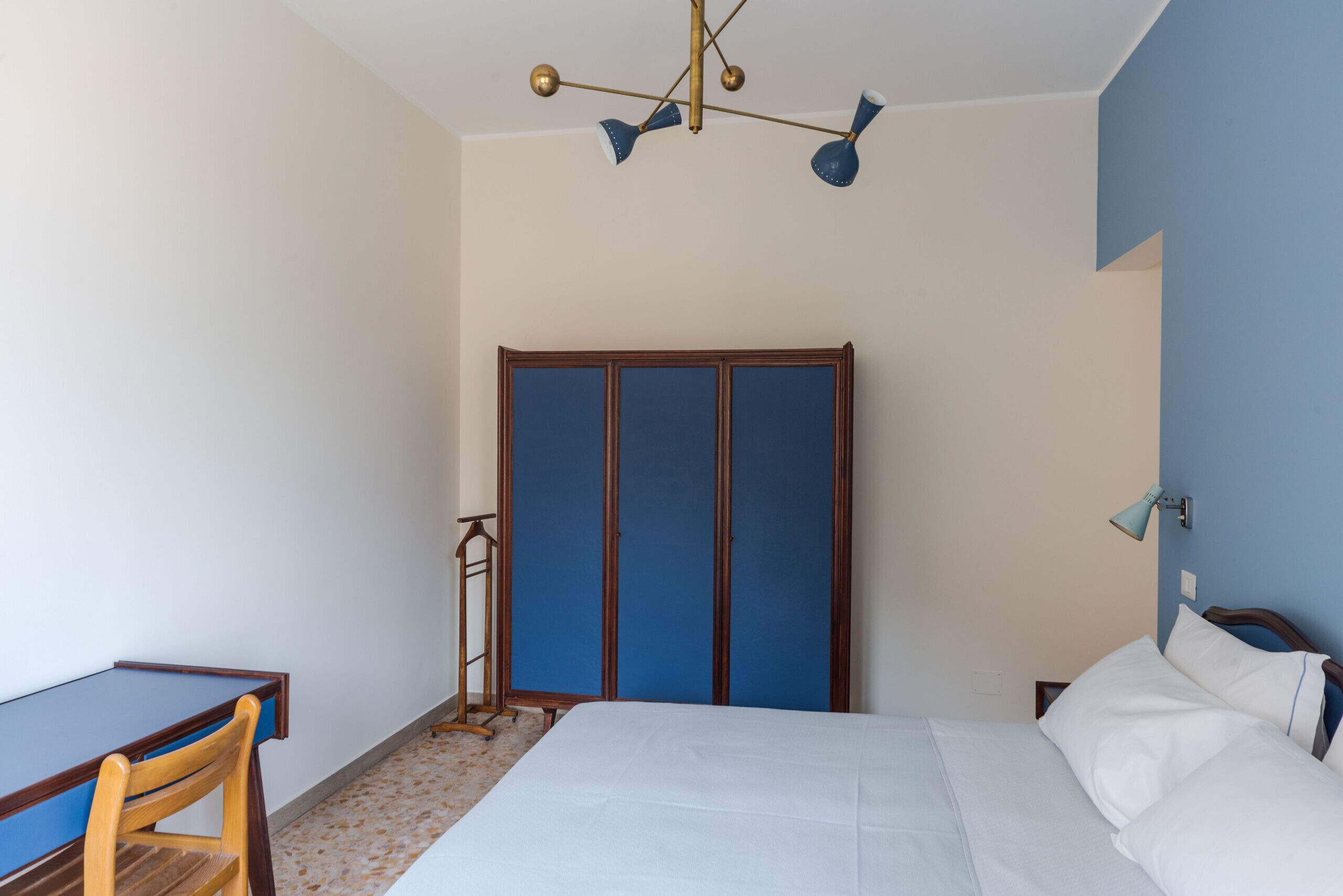 A bedroom with a bed, a desk, and a wardrobe.