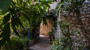 A stone staircase leading up to a door, surrounded by lush greenery and potted plants. - Giardino Degli Aranci With Terrace by Wonderful Italy (Taormina)