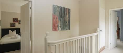 A bedroom with a bed, a nightstand, and a painting on the wall.