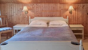 Un dormitorio con paneles de madera, una cama, dos mesitas de noche y dos lámparas de pared.