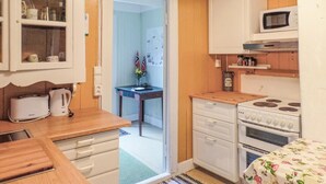 Cocina pequeña con microondas, estufa y armarios de madera.