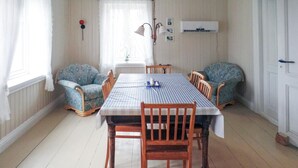 Un comedor con mantel a cuadros, sillas de madera y sillones estampados.