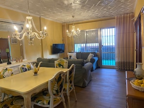 Un salon comprenant une table à manger, des chaises, un canapé et un téléviseur.