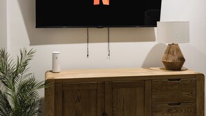 Ein Flachbildfernseher an der Wand, darunter ein Holzschrank.