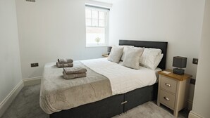 Ein Schlafzimmer mit Bett, Nachttischen, einem Fenster und einer Lampe.