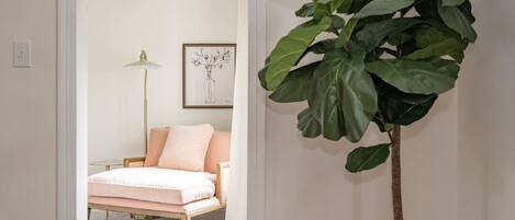 A bedroom with a bed, a floor lamp, and a large plant.