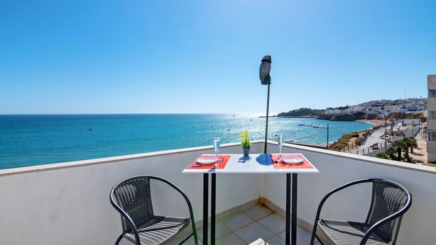 A balcony with a table set for two, overlooking a coastal view. - Apartment 'Vista Mar' with Sea View, Wi-Fi and Air Conditioning (Albufeira)