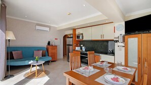 A modern kitchen with a dining area, a sofa, and a small table with a plant. - Apartment 'Vista Mar' with Sea View, Wi-Fi and Air Conditioning (Albufeira)