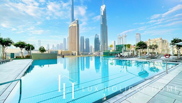 A swimming pool with a city skyline in the background, including the Burj Khalifa. - LUX The Downtown Zabeel View Suite (Dubai)