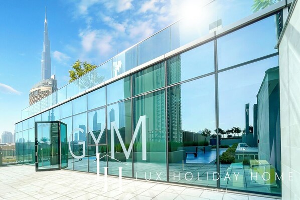 A modern building with large glass windows and the text "GYM LUX HOLIDAY HOME" on the facade. - LUX The Downtown Zabeel View Suite (Dubai)