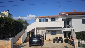 A modern two-story house with a car parked in the driveway, a staircase leading to the entrance, and a small outdoor seating area. - Apartment Fuzalo · Relax & BBQ by Villas Guide (Krnica)