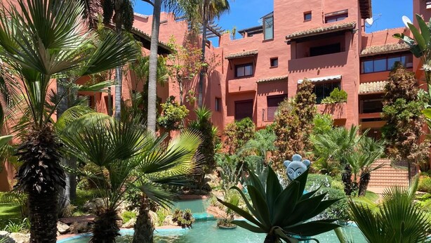 A resort with a pool surrounded by palm trees and a building with balconies. - Apartment 'Don Carlos Marbella Beach' with Shared Pool, Wi-Fi and Air Conditioning (Marbella)