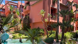 A courtyard with a water feature, lush greenery, and a building with balconies. - Apartment 'Don Carlos Marbella Beach' with Shared Pool, Wi-Fi and Air Conditioning (Marbella)
