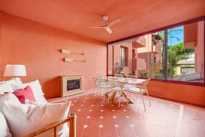 Une pièce comprenant un lit, une table à manger avec des chaises, un ventilateur de plafond et une cheminée.