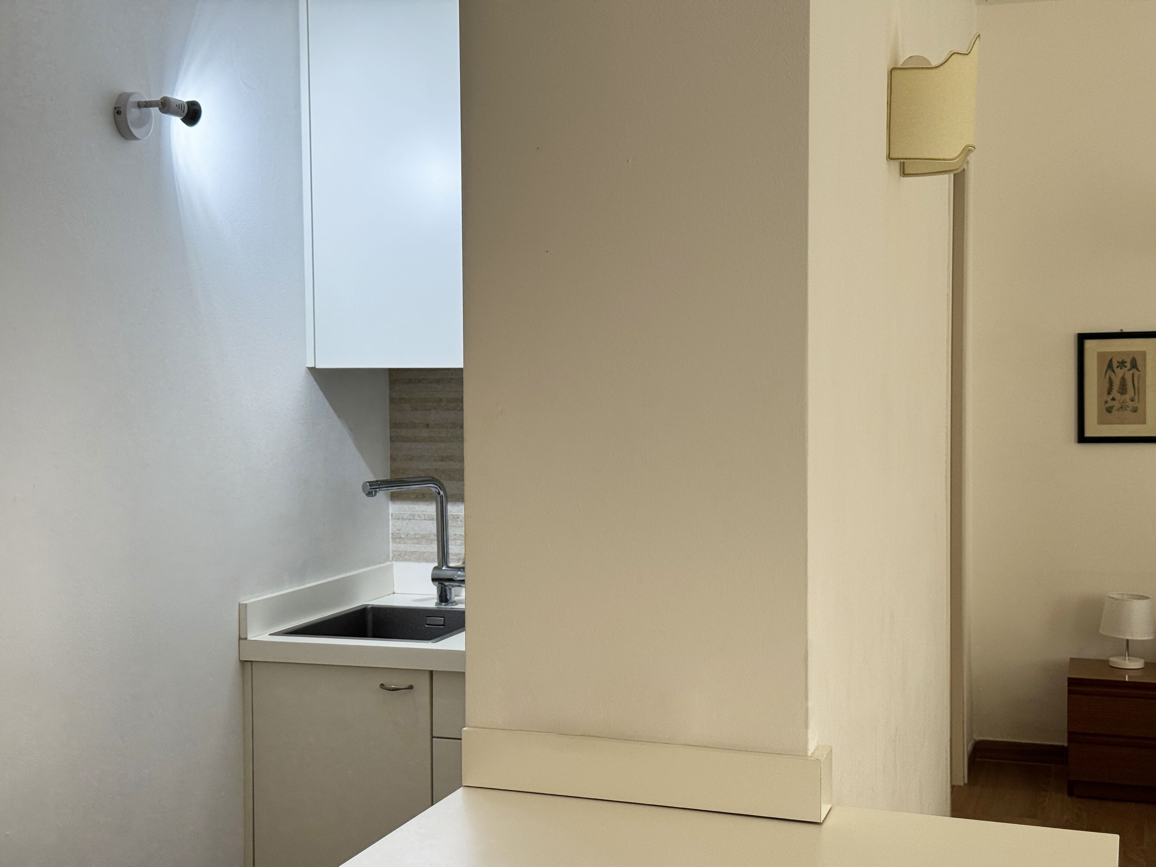 Una cocina moderna con encimera blanca, un fregadero y un armario.