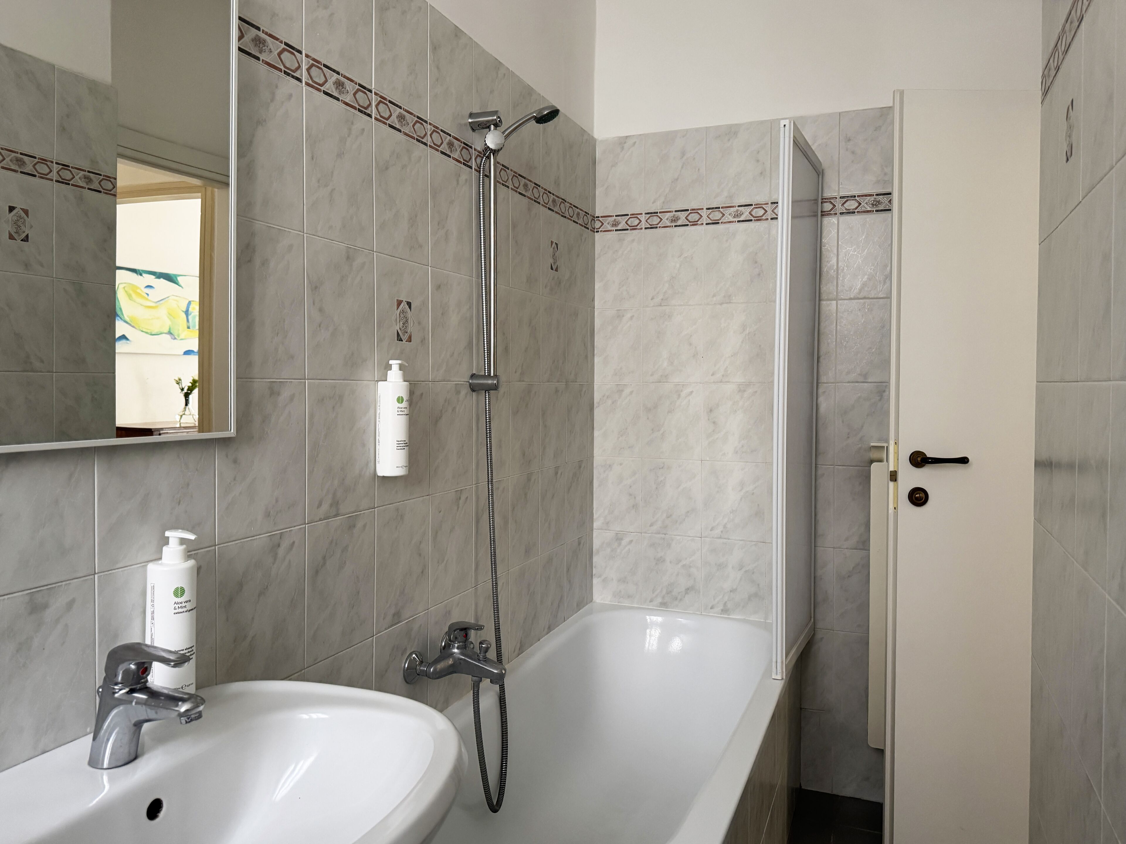 A bathroom with a white bathtub, a sink with a faucet, and a showerhead.