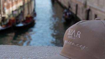 A canal with buildings on either side, a boat, and a cap with embroidered text.