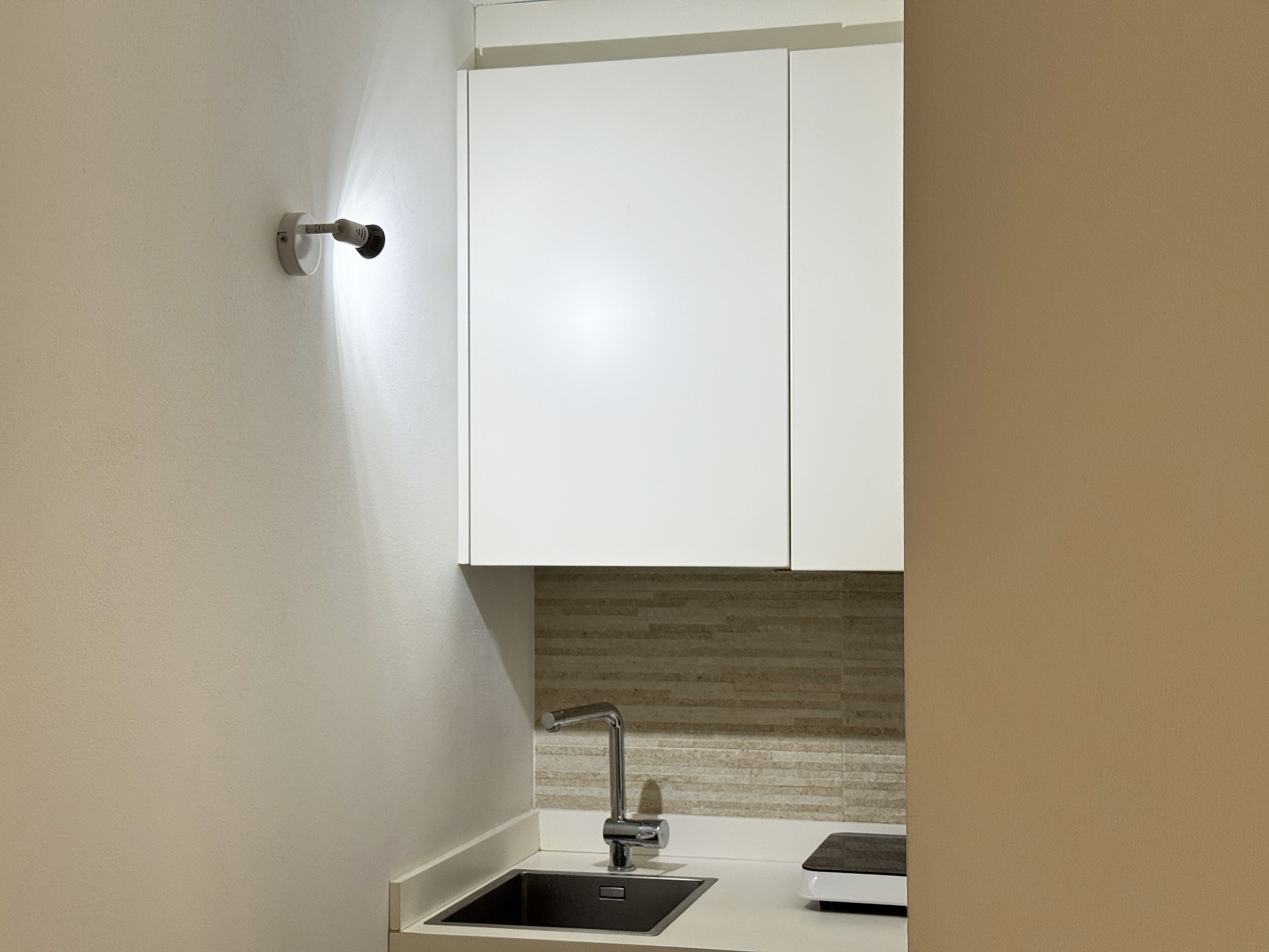 A modern kitchen with white cabinets, a stainless steel sink, and a tiled backsplash.