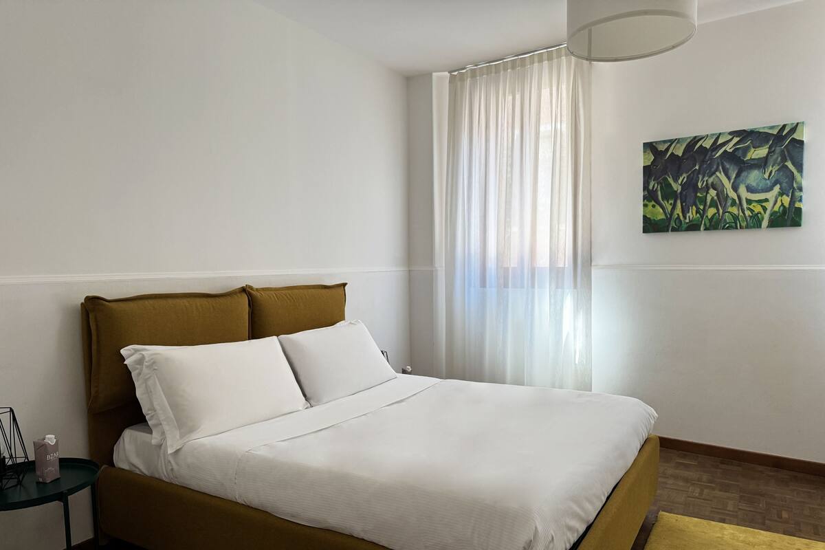 A bed with a headboard, white bedding, and a yellow rug.