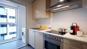 A modern kitchen with a built-in washing machine, stainless steel appliances, and a large window providing natural light. - Vita Homes by Upper Luxury Housing (Santiago de Compostela)