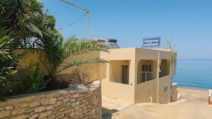 A building with a stone wall, a sign for "HANODEMA 3 APARTMENTS," and a view of the sea. - Beachfront Panorama Double Room in Kythira (Kithira)