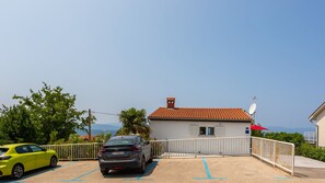 A parking area with a building that has a red-tiled roof and a satellite dish.