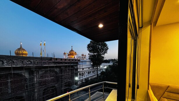 A balcony with a view of a historic building with golden domes, a bridge, and a tree.