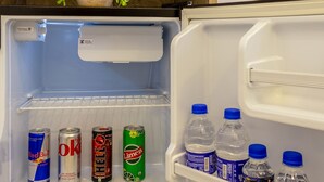 Un réfrigérateur ouvert, avec une étagère remplie de boissons et une plante en pot.