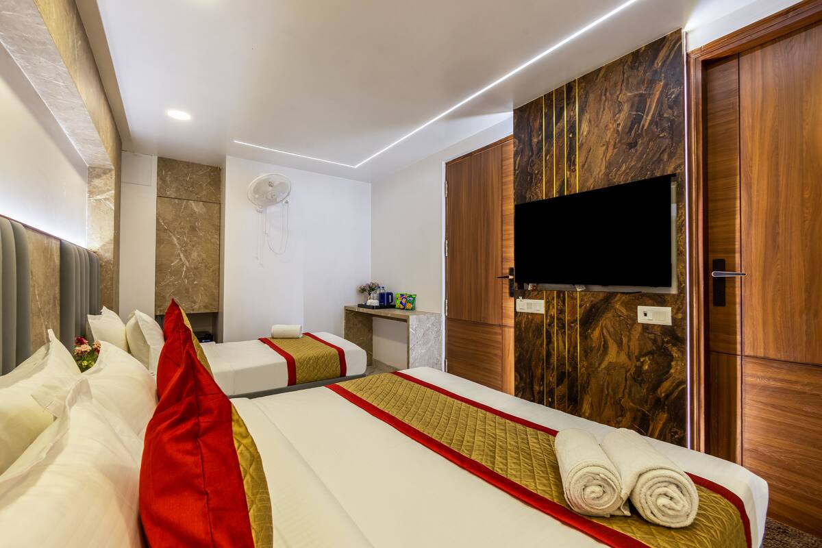 Habitación de hotel con dos camas, televisión, minibar y armario de madera.
